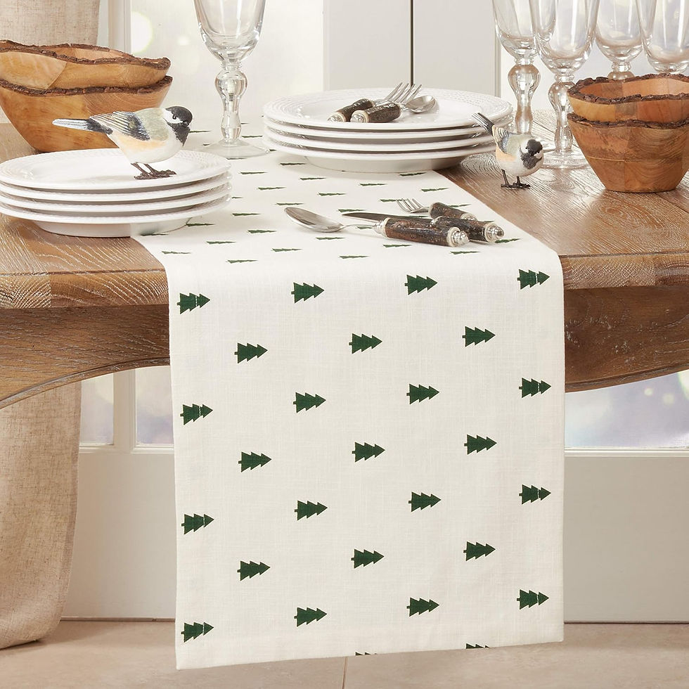 Festive table set with white plates, glasses, and cutlery on a wood table. A white runner with green tree pattern and decorative birds.