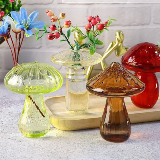 Mushroom-shaped glass vases hold vibrant flowers and berries on a wooden tray. Colors include green, amber, and red. Brick wall backdrop.