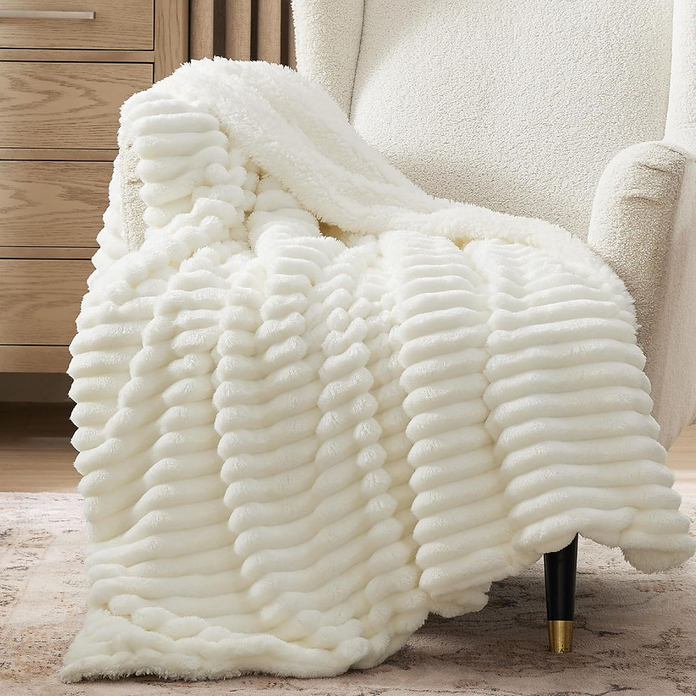 Plush white blanket with ribbed texture draped over a cream armchair. Wooden cabinet in background, creating a cozy, serene setting.