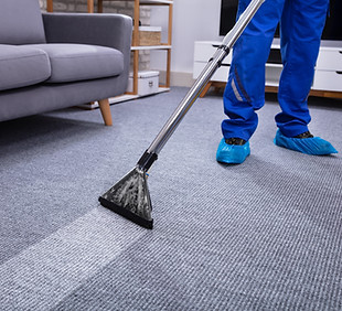 Low Section Of A Male Janitor Cleaning Carpet With Vacuum Cleaning In The Living Room.jpg