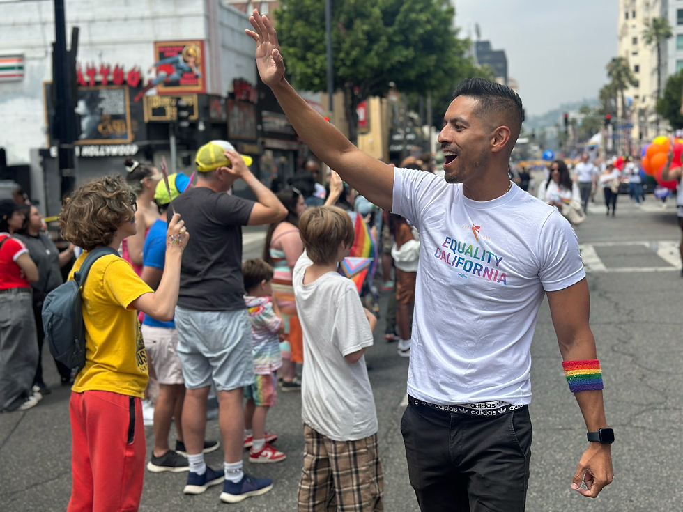 Juan Camacho waving and marching with Equality California at the Los Angeles Pride Parade