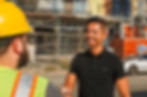 Juan Camacho shaking hands with a construction worker in front of a worksite