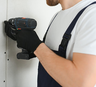 Worker builder installs plasterboard drywall at a construction..jpg