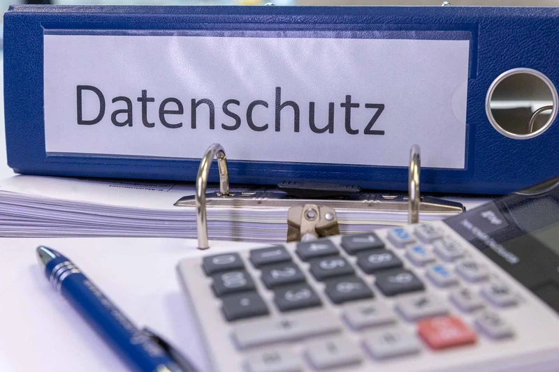 Blaue Datenschutz-Ordner mit Dokumenten und Rechner