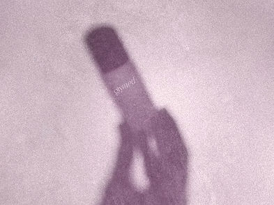 A shadow of a hand holding a Glymed Plus product bottle on a purple backdrop