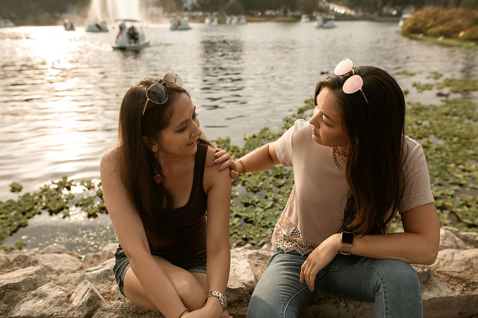 Two women talking by a lake offering emotional support while coping with anxiety and improving mental wellness outdoors