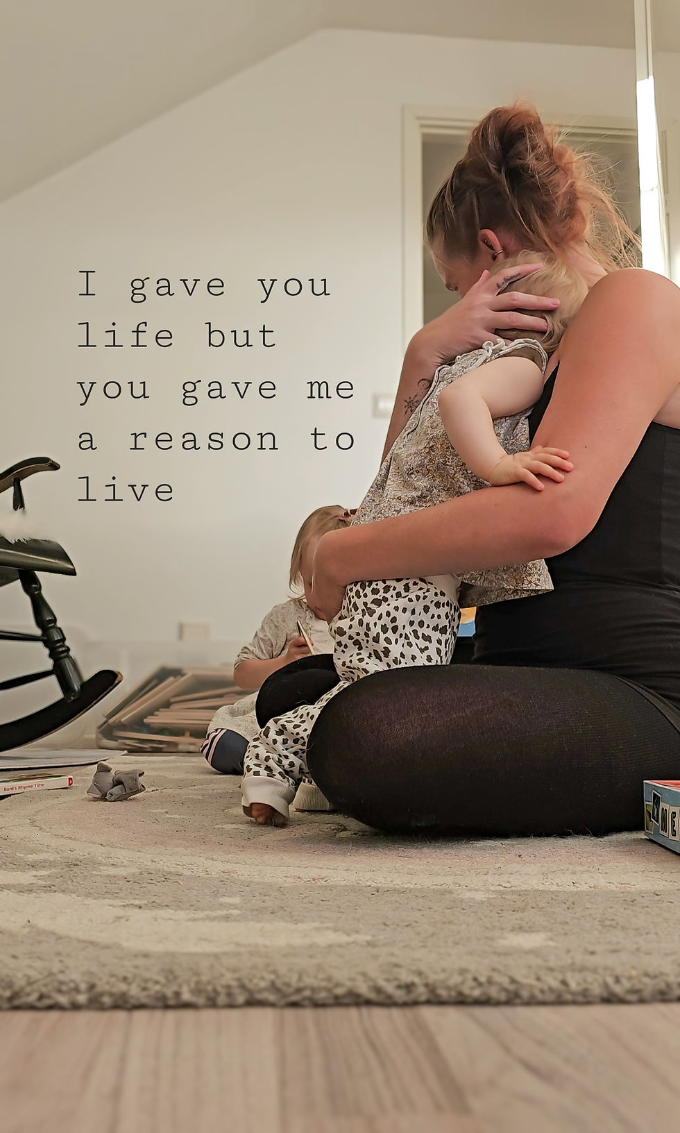 Äiti halaa lasta lattialla. Taustalla keinuhevonen, vaaleat seinät. Teksti: "I gave you life but you gave me a reason to live". Tunnelma lämmin.