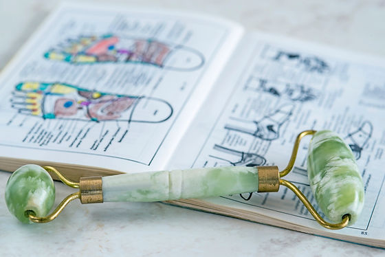 jade roller placed on top of a reflexology book