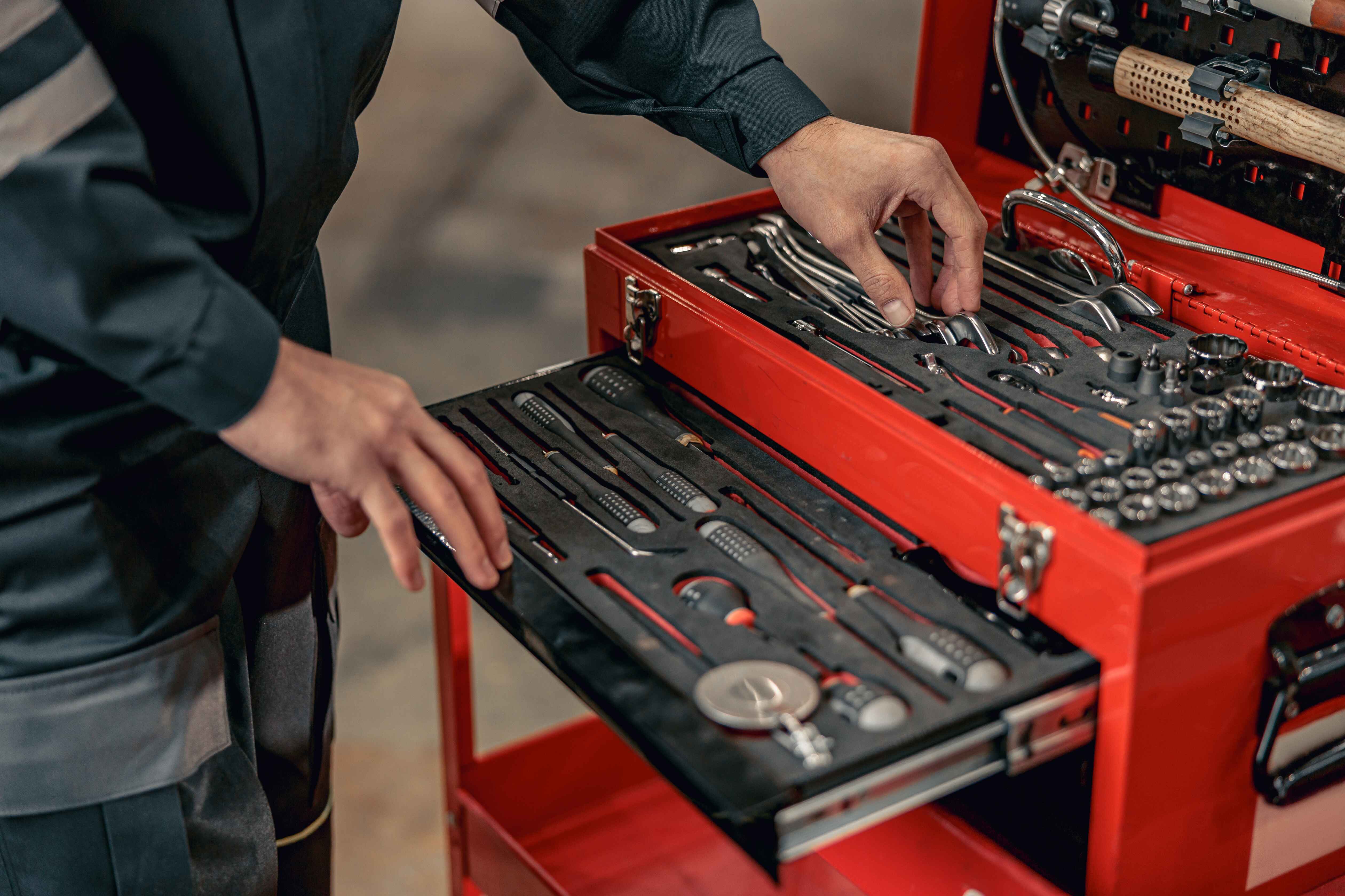 Aviation mechanic reaching into tool box, within an airplane hangar.