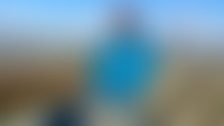 A male student standing on top of a stone hill fort with the Donegal landscape far behind him.