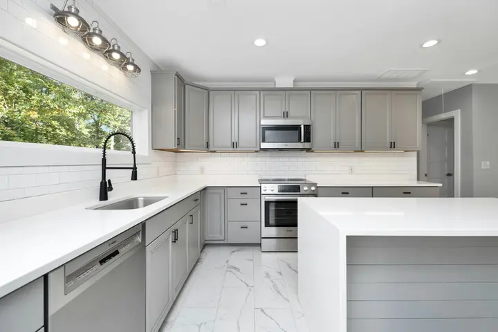 Gray kitchen with white quartz counters, marble-look floor tile and peninsula