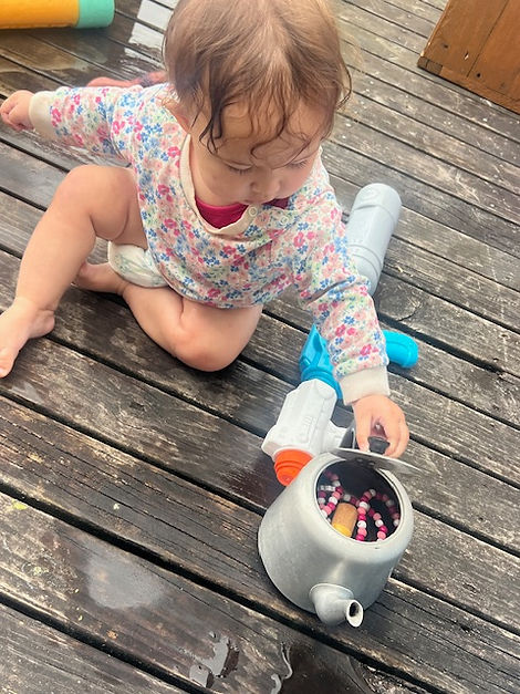 A toddler playing with an old teapot