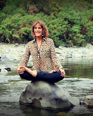Christine Balzer-Gibbs in lotus pose on a rock in the middle of a river
