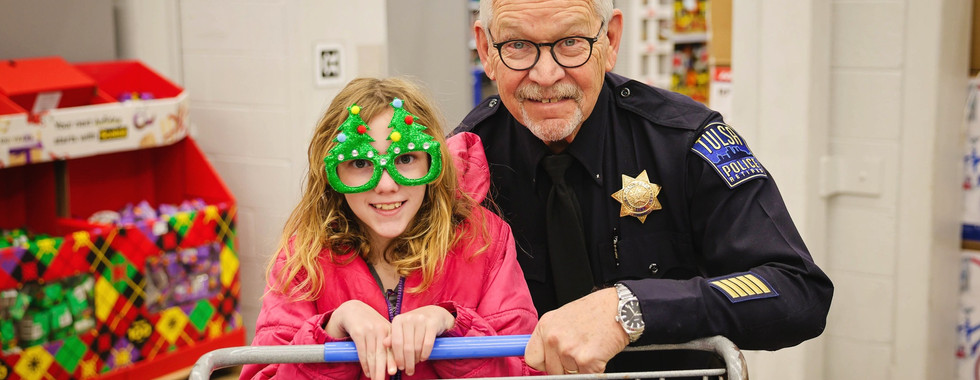 A child pushing a shopping cart with a retired Tulsa Officer