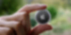 A stock photo of a person holding up an Apple AirTag.