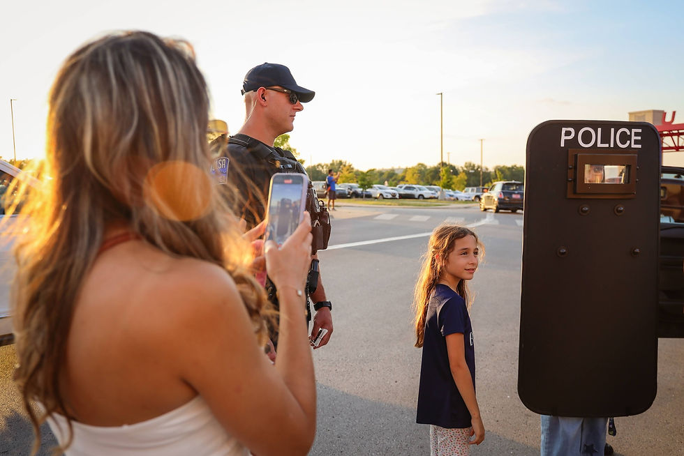 Attendees of a community event taking photos with a Tulsa Police shield.