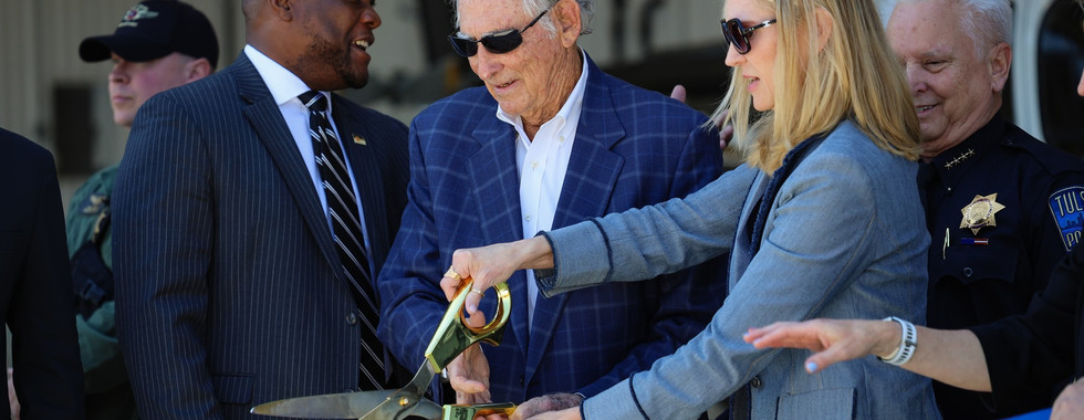 A close angle of city leaders cutting the ribbon at the hangar.