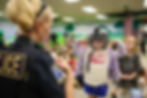 A Tulsa Police Officer letting a preschool student wear a police helmet