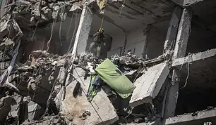 A rescue worker navigates the rubble of a collapsed building following a missile strike