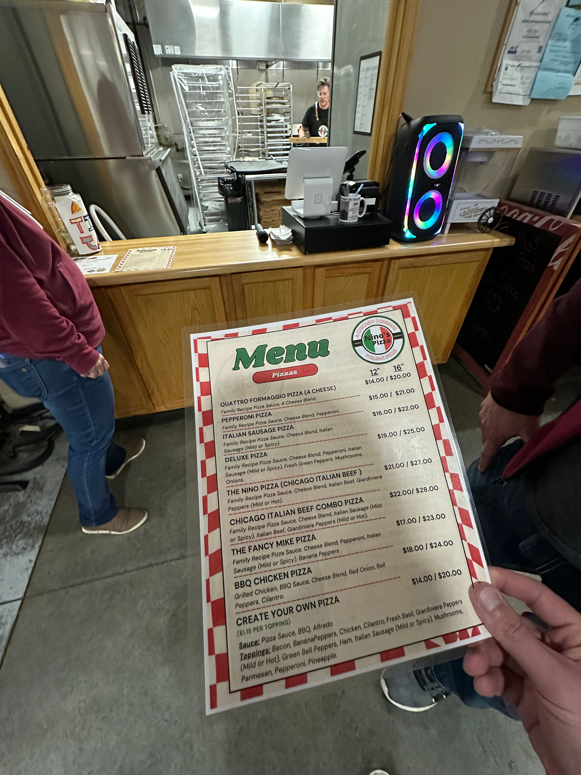 Holding the menu for nino's pizza in front of the order window