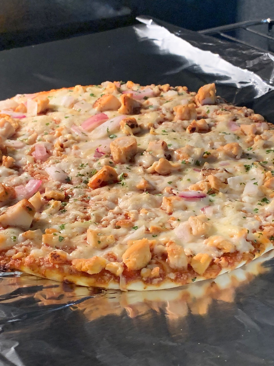 pizza cooking in oven with chicken and bbq sauce
