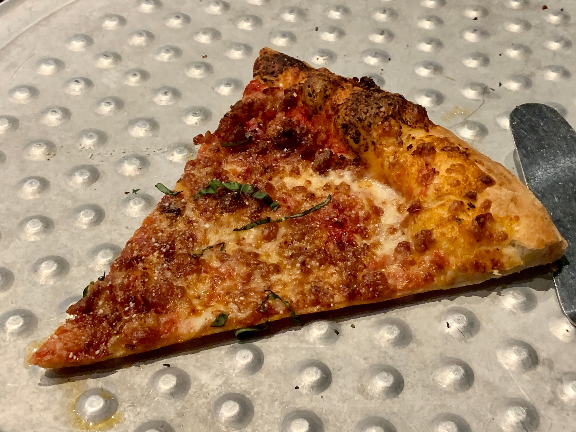 slice of pizza on silver tray with raised dots