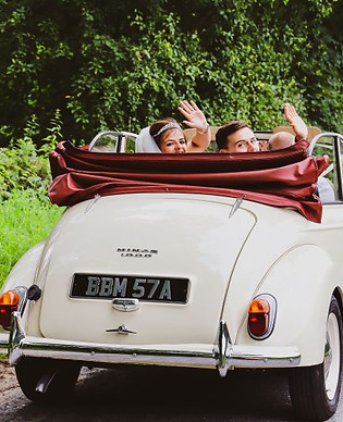 Married couple driving away in vintage car