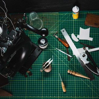 Leathercraft tools and machine on a green cutting mat, ready for use.