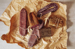 An assortment of artisanal cured meats displayed on crinkled brown parchment paper