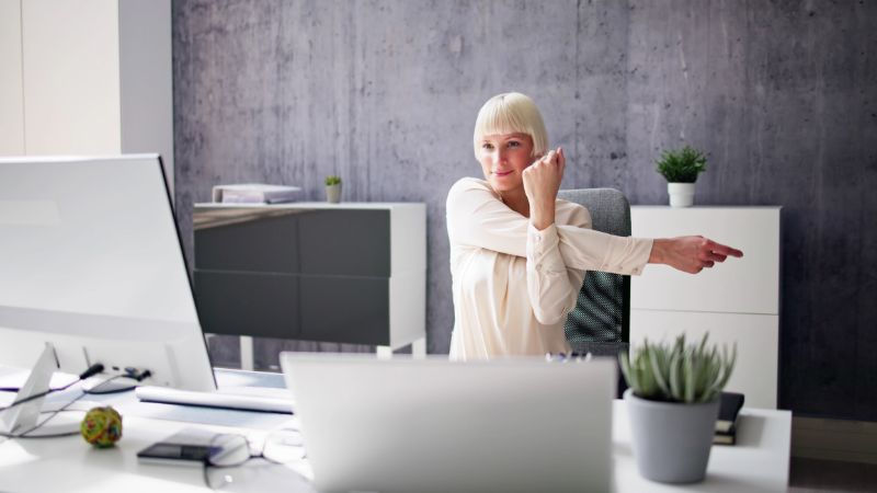 Woman doing a rear delt stretch at her desk