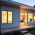 SModern house exterior with a soft glowing interior visible through large windows, warm in