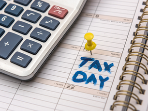 Calculadora junto a agenda con "TAX DAY" en azul y chincheta amarilla. Ambiente de organización y planificación financiera.