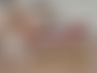 Hand holds red upward arrow over stacked coins on a wooden desk, suggesting growth. Blurred background with a calculator and notebook.