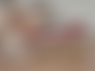 Hand holds red upward arrow over stacked coins on a wooden desk, suggesting growth. Blurred background with a calculator and notebook.