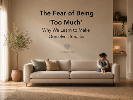 Woman sitting curled up on the edge of a large sofa in a warm, minimalist living room with ample empty space around her