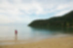 Person standing at the edge of a calm tropical beach