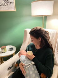 A woman in a rocking chair feeding a bottle to a newborn baby.