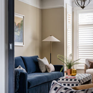 Cozy living room with blue sofa and patterned ottoman.