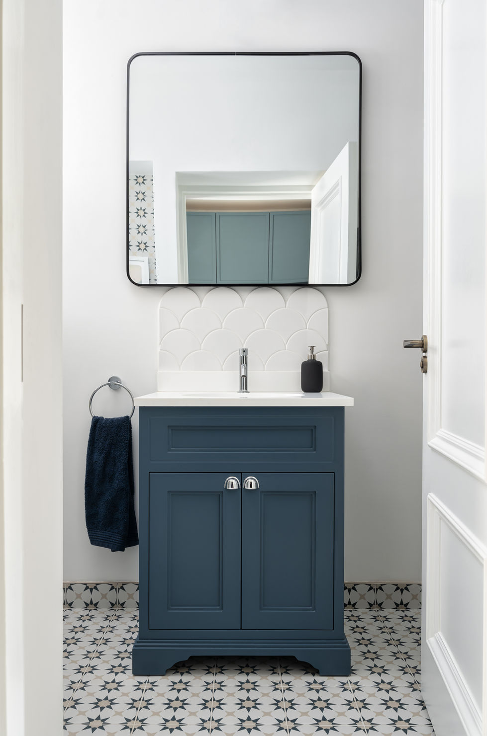 Small bathroom with blue vanity and large mirror.