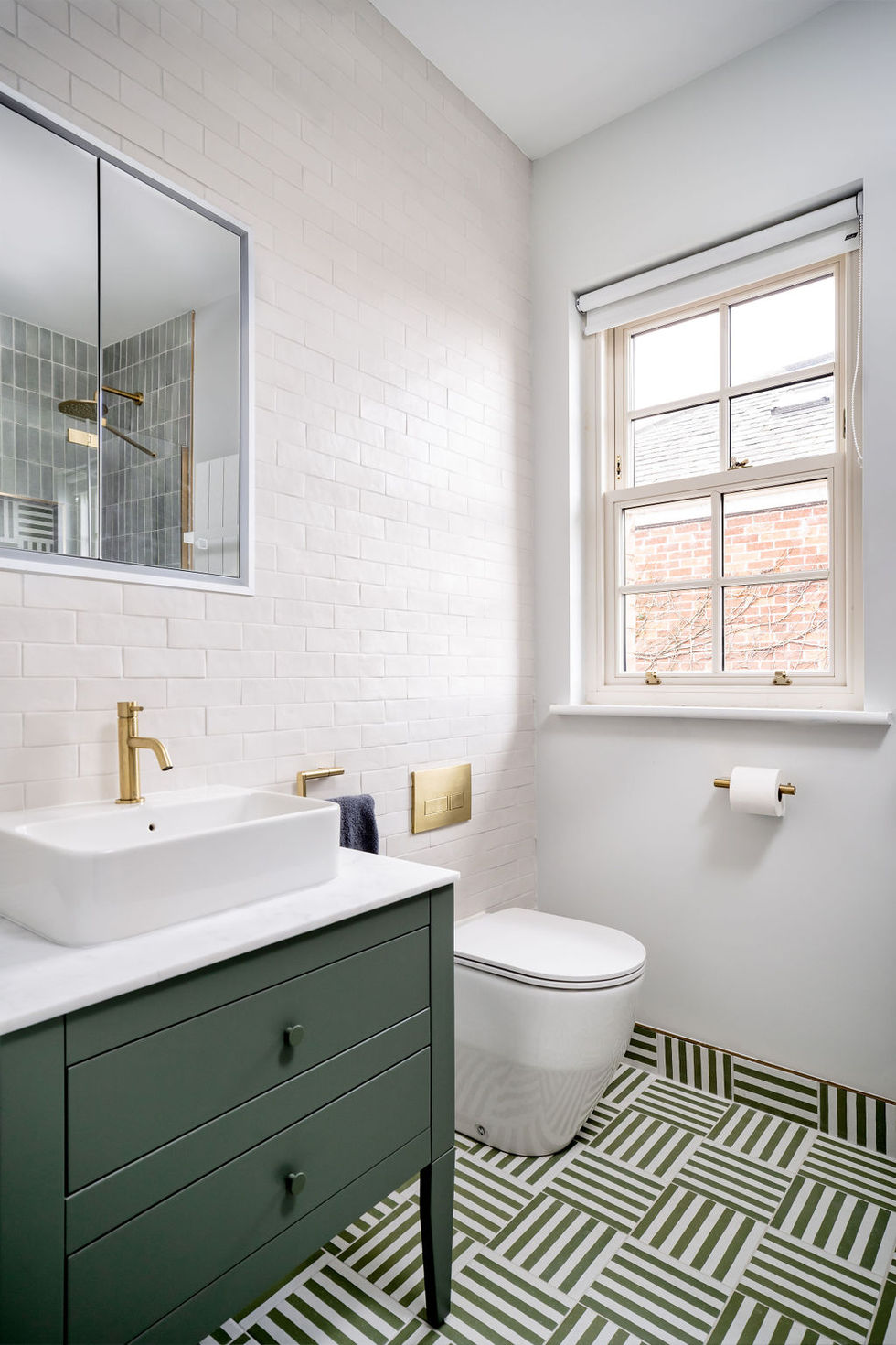 Modern bathroom with green vanity and geometric floor tiles.
