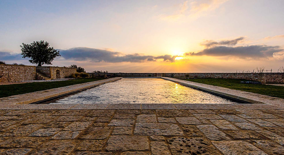 KORE_Piscina. Costruzione in pietra leccese. Pool. Sunrise on the pool. Lime stone construction Puglia. The sun rays dance on the ripples of water creating hypnotic beams of light. Let yourself be lulled as the sun peeks out from behind the horizon. - Il sole danza sull’increspature dell’acqua, creando luccichii ipnotici. Cullati mentre la luce si affaccia sull’orizzonte.