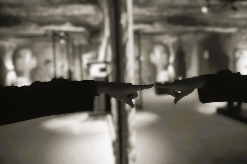 A finger pointing in a mirror with a reflection