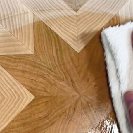 A detailed view of an artisan applying the best oil for cutting board preservation to a Key Home Goods proprietary patterned end-grain board.