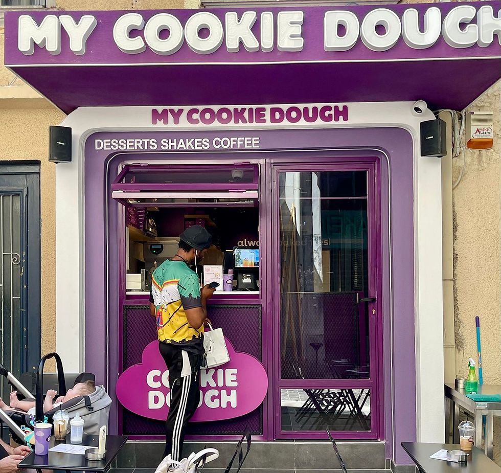 Fachada de tienda pequeña moderna con letrero iluminado y colores llamativos, ejemplo de diseño retail para atraer clientes desde el exterior.
