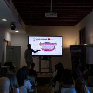 Ponente explicando en un curso para dentistas en una sala oscura