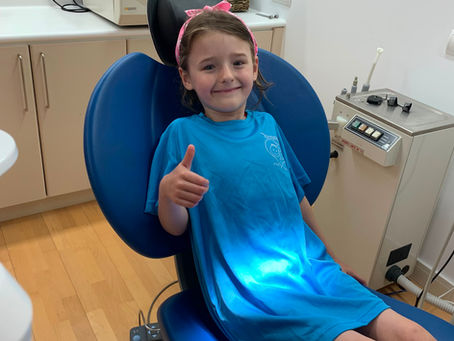 Un niño sentado en una silla de odontólogo a punto de ser revisado por un destista voluntario en el CODB.