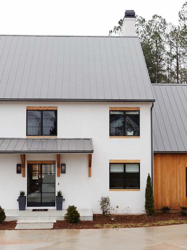 Front exterior of a modern house with white stucco, wood siding, and a gray metal gable roof. Central double glass door entry with small roof and planters.
Palmer Kay Design_Interior Design_Peachtree City, GA