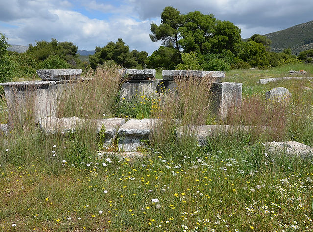 Stone ruins in a green meadow at the Sanctuary of Asclepius at Epidaurus
