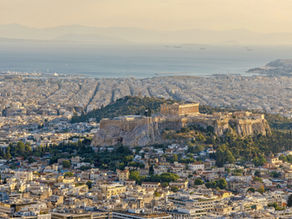 The Acropolis and central Athens seen from Lycabettus Hill in warm evening light, with the Saronic Gulf behind
