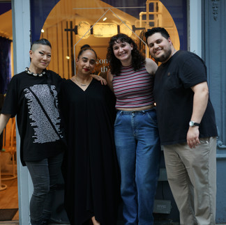 Four people smiling in front of the "common things" entrance, standing together as a team.